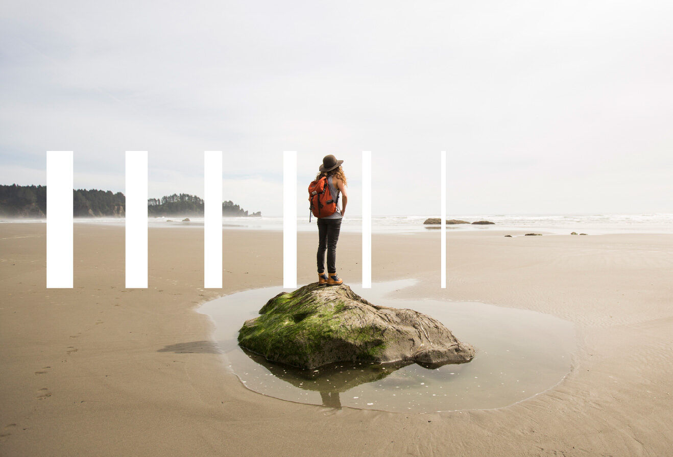 a woman with a backpack on a rock at the beach