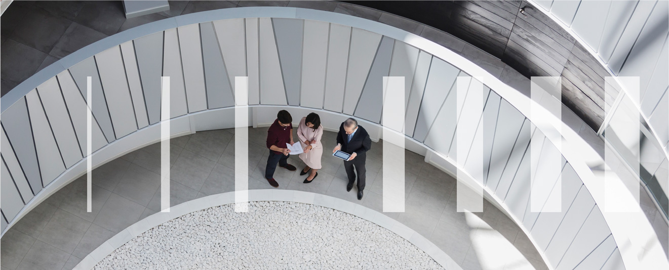 Three business people looking at a tablet and reports