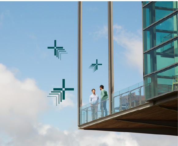 Two men in a high-rise building with the sky with clouds behind them, having a discussion implying collaboration